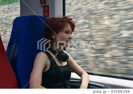 young woman rides in a moving suburban train, outside the window - a gabion wall blurred in motion young woman rides in a moving suburban train, outside the window - a gabion wall blurred in motion 93006288
