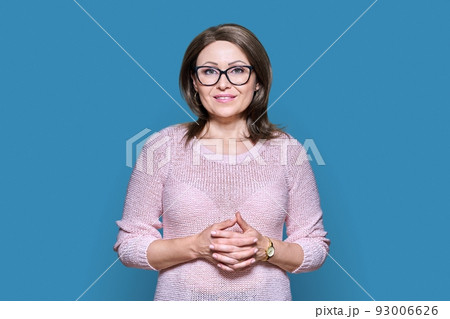 Attractive Middle aged woman looking at camera on blue background 93006626