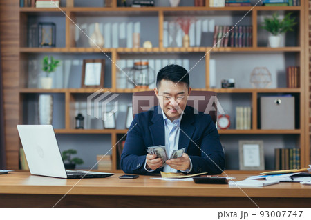 Satisfied young man asian office worker received money, salary, cash reward in an envelope, counts Satisfied young man asian office worker received money, salary, cash reward in an envelope, counts 93007747