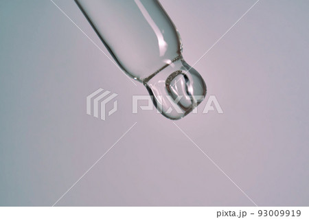 serum pipette close-up with falling drop on purple background serum pipette close-up with falling drop on purple background 93009919