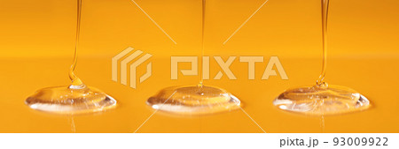 Three drops of body gel or shampoo pouring from above on a yellow saturated background. Banner. 93009922