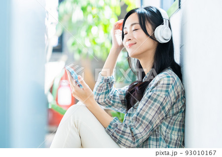 女性　ライフスタイル　スマホ　ヘッドフォン　音楽　リビング 93010167