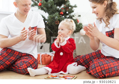 Toddler child with cochlear implant plays with parents under christmas tree - deafness and innovating medical technologies for hearing aid 93010621