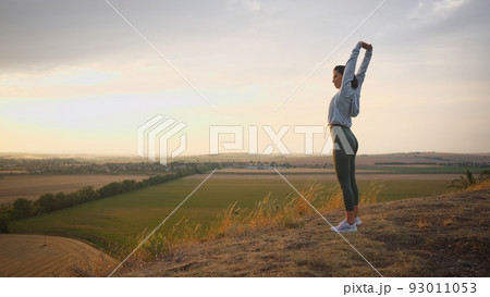 Caucasian female runner standing and warming up in preparation for a jogging run Caucasian female runner standing and warming up in preparation for a jogging run 93011053