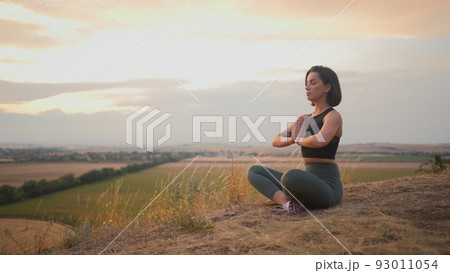 Calm serene sporty young woman meditate while sitting in namaste pose with eyes closed 93011054