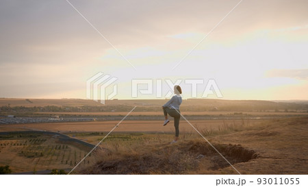 Female runner warming-up her legs on a high mountain during the sunset Female runner warming-up her legs on a high mountain during the sunset 93011055
