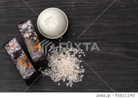 Bars of beautiful natural handmade soap, salt and bomb on a black wooden background Bars of beautiful natural handmade soap, salt and bomb on a black wooden background 93011140