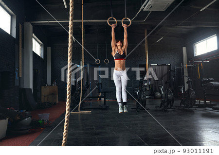 Female Athlete Performing Pull-ups on Gymnastic Rings 93011191