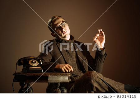 Retro style portrait of young man, writer and traveler wearing vintage style clothes isolated over dark brown background. Business, art, fashion concept 93014119