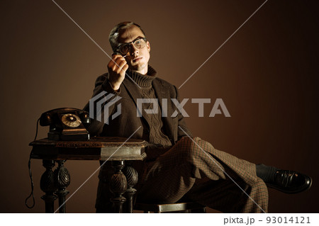 Retro style portrait of young man, writer and traveler wearing vintage style clothes isolated over dark brown background. Business, art, fashion concept Retro style portrait of young man, writer and traveler wearing vintage style clothes isolated over dark brown background. Business, art, fashion concept 93014121