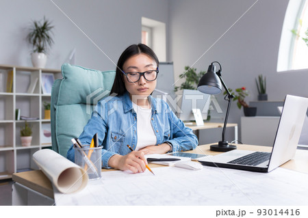 Asian designer working in office, with blueprints, woman at work in casual clothes. Asian designer working in office, with blueprints, woman at work in casual clothes. 93014416
