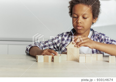 Little boy raises his hand to the house from wooden cubes Little boy raises his hand to the house from wooden cubes 93014674