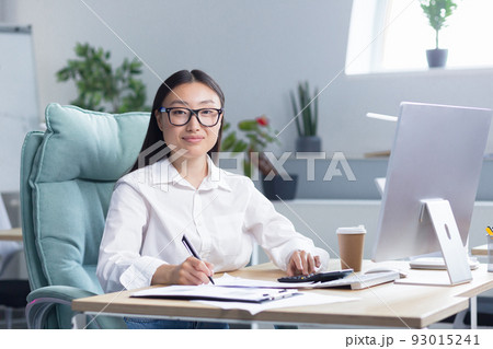 Portrait of young beautiful and successful Asian business woman, female employee smiling and looking at camera, accountant financier paperwork. Portrait of young beautiful and successful Asian business woman, female employee smiling and looking at camera, accountant financier paperwork. 93015241