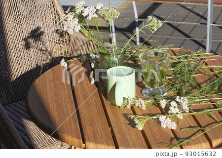 Balcony table with Yarrow plants and glass of yarrow herb tea. 93015632