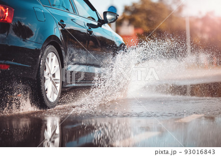 Car driving through the puddle and splashing by water. 93016843