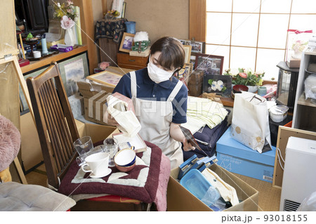 散らかった部屋の片付けをする女性作業員 散らかった部屋の片付けをする女性作業員 93018155