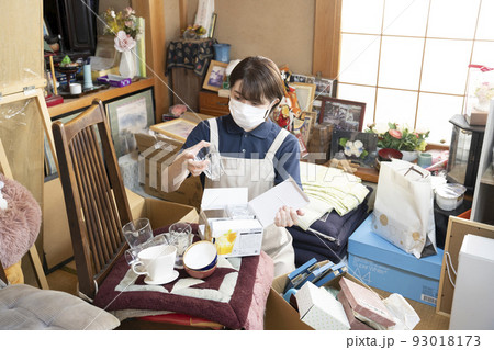 散らかった部屋の片付けをする女性作業員 散らかった部屋の片付けをする女性作業員 93018173