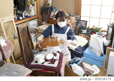 散らかった部屋の片付けをする女性作業員 93018174