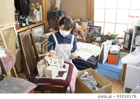 散らかった部屋の片付けをする女性作業員 散らかった部屋の片付けをする女性作業員 93018176