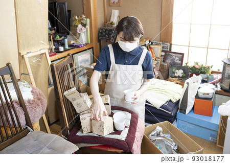 散らかった部屋の片付けをする女性作業員 93018177