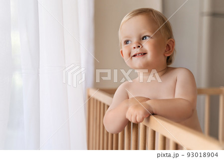 Home portrait of cute little baby boy in bed with pensive face looking at copy space 93018904