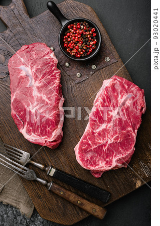 Raw fresh meat Top Blade steaks, on black dark stone table background, top view flat lay Raw fresh meat Top Blade steaks, on black dark stone table background, top view flat lay 93020441