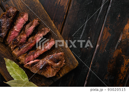 Beef steak. Grilled beef steak striploin medium rare, on old dark wooden table background, top view flat lay, with copy space for text Beef steak. Grilled beef steak striploin medium rare, on old dark wooden table background, top view flat lay, with copy space for text 93020515