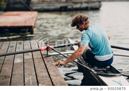 Sportsman single scull man rower prepare to training competition with boat on pier river 93020870