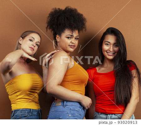 young pretty african and caucasian women posing cheerful together on brown background, lifestyle diverse nationality people concept close up 93020913