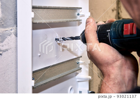 Power drill at electrical work is used to drilling hole in distribution board. 93021137