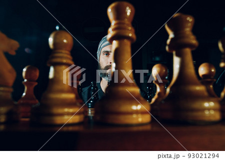 Young adult man playing chess in dark with side lit. Young adult man playing chess in dark with side lit. 93021294