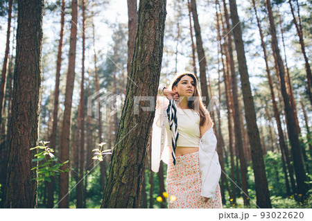 Young beautiful hippie woman walks in the summer forest laughs dances and enjoys life and nature Young beautiful hippie woman walks in the summer forest laughs dances and enjoys life and nature 93022620