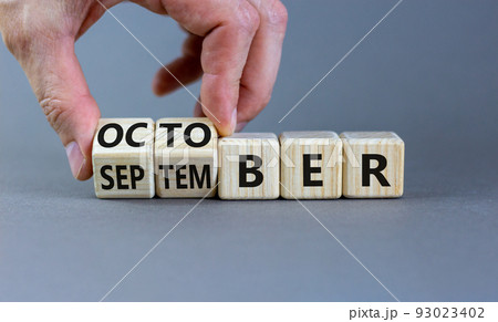 Symbol for the change from September to october. Businessman turns wooden cubes and changes the word 'September' to 'October'. Beautiful grey background, copy space. Happy October concept. 93023402