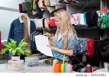 A seamstress cuts a paper mold from the garment she is designing. A seamstress cuts a paper mold from the garment she is designing. 93023661