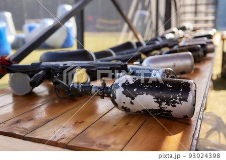Close up of paintball gun, special balls and protective mask, equipment for playing paintball on a wooden table, action game concept. Close up of paintball gun, special balls and protective mask, equipment for playing paintball on a wooden table, action game concept. 93024398