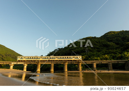 朝焼けの宮崎県日南市山王浜の波打ち際の隈谷川橋梁を走る日南線キハ40 93024657