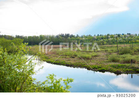 a small river next to a green field and a forest in summer 93025200
