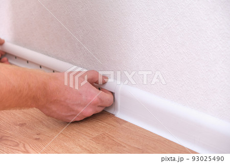 A man installs a floor skirting board. Fixing the 93025490