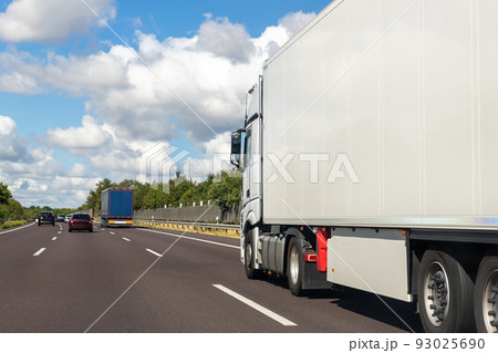 White blank modern delivery big shipment cargo commercial semi trailer truck moving fast on motorway road city urban suburb. Business distribution logistics service. Lorry driving highway sunny day White blank modern delivery big shipment cargo commercial semi trailer truck moving fast on motorway road city urban suburb. Business distribution logistics service. Lorry driving highway sunny day 93025690