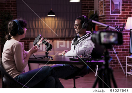 Man and woman recording podcast conversation on camera, vlogging discussion for social media content. Lifestyle blogger and female guest filming live broadcast stream on channel. 93027643