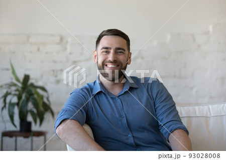 Happy handsome man sitting on home couch, looking at camera 93028008