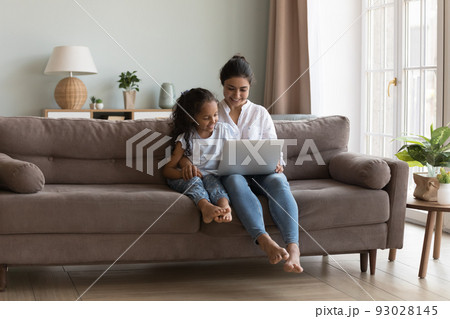 Happy pretty Indian mother showing learning app to little daughter Happy pretty Indian mother showing learning app to little daughter 93028145