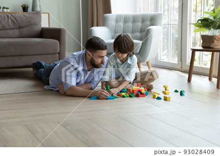 Dad and son play wooden bricks at home 93028409