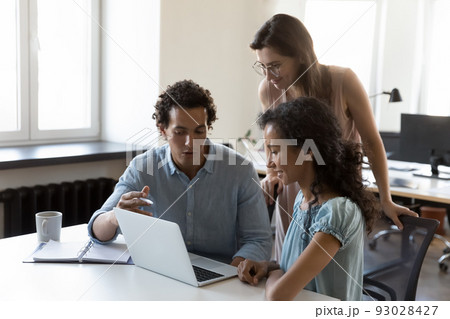 Three office employees discussing strategy, working on project using laptop Three office employees discussing strategy, working on project using laptop 93028427