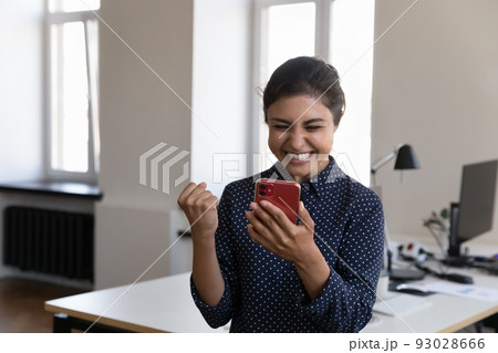 Indian woman employee read great news on smartphone feels overjoyed Indian woman employee read great news on smartphone feels overjoyed 93028666