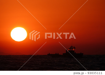 夕暮れの室戸沖に沈む夕日と漁船 93035111