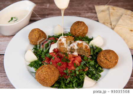 Vegetarian dish, falafel balls from spiced chickpeas with chopped parsley, fresh onions and tomato 93035508