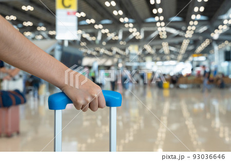 Woman hand holding baggage handle with blurred airport terminal background. Woman hand holding baggage handle with blurred airport terminal background. 93036646