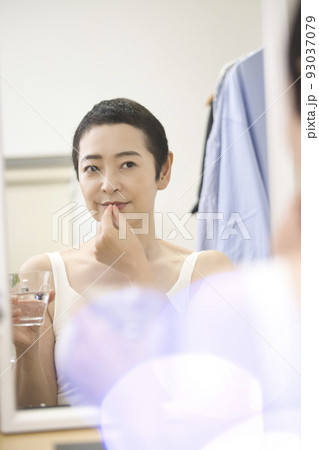 ビューティ　鏡の前で薬を飲むショートヘアのミドル女性 93037079