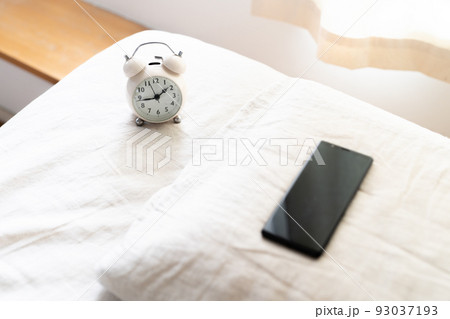 ベッドに置かれたスマホと目覚まし時計 ベッドに置かれたスマホと目覚まし時計 93037193